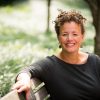 Author Ali Michael is pictured sitting on a bench outdoors.