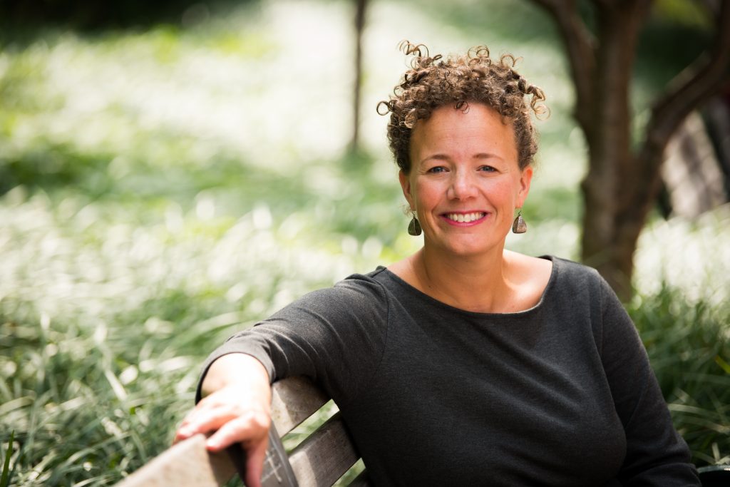 Author Ali Michael is pictured sitting on a bench outdoors.