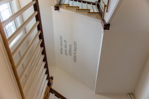 Photograph of Allana Clarke's art work in a stairwell in the Williamstown Municipal Building. "Who would you be if Others didn't hurt?" 2017. Vinyl on wall, dimensions variable.