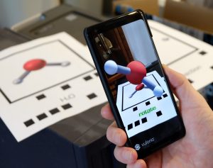 A photo showing how a phone app can read a two dimensional code and turn it into a three dimensional image on the phone screen. 