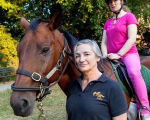 Alicia Kershaw, Williams Class of 1975, is founder of GallopNYC. Here she is seen with a horse ridden by a therapeutic riding student