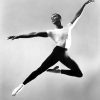 A black and white photo of dancer Arthur Mitchell leaping in mid-air.
