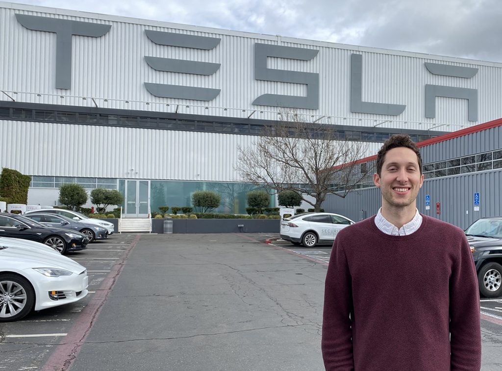 Photo of alumnus Dan Wohl standing outside a Tesla building