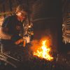 A photo of Jordan Lamothe working near an open fire to create his wares.