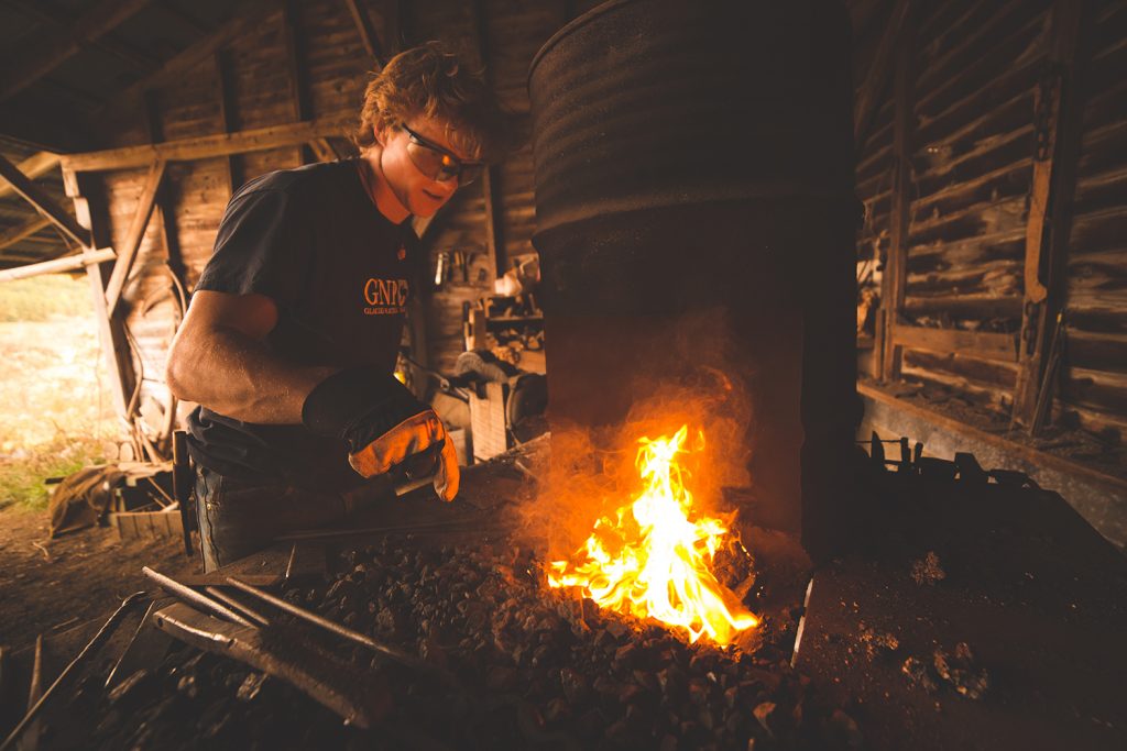 A photo of Jordan Lamothe working near an open fire to create his wares.