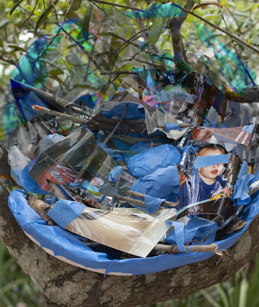 Photo of sculpture made from a variety of items including blue tabe and photographs.