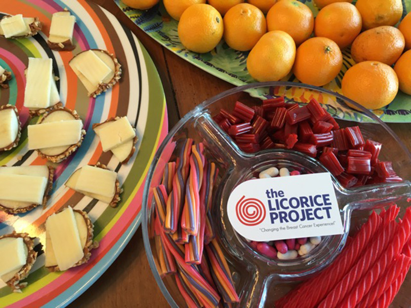 Photograph of the Licorice Project logo on a plate of licorice, accompanied by hors d'oeuvres.