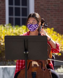 Grace Kim, Class of 2023, performs the cello while wearing a mask in front of the Paresky Center in October.