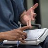 A detail photograph of a student inmate's hands at the Berkshire County House of Corrections, where Williams students are tutoring inmates who are about to be released and are taking a high school equivalency exam called HiSET.