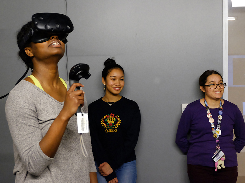 A photo of students in Professor Christorpher Goh's Introductory Chemistry course using virtual reality to learn about molecules. The student in the foreground wears black goggles and is looking up at the ceiling.
