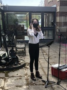 Student singing in an outdoor recording studio.