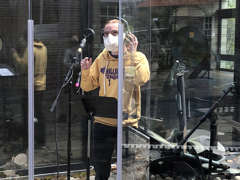 Student singing in an outdoor recording booth.