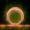 An aerial view of the Memorial to Enslaved Laborers at the University of Virginia shows a circular brick wall lined by lights all around, with a grassy lawn in the middle.