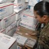 Military personnel sort mail to be delivered to troops.