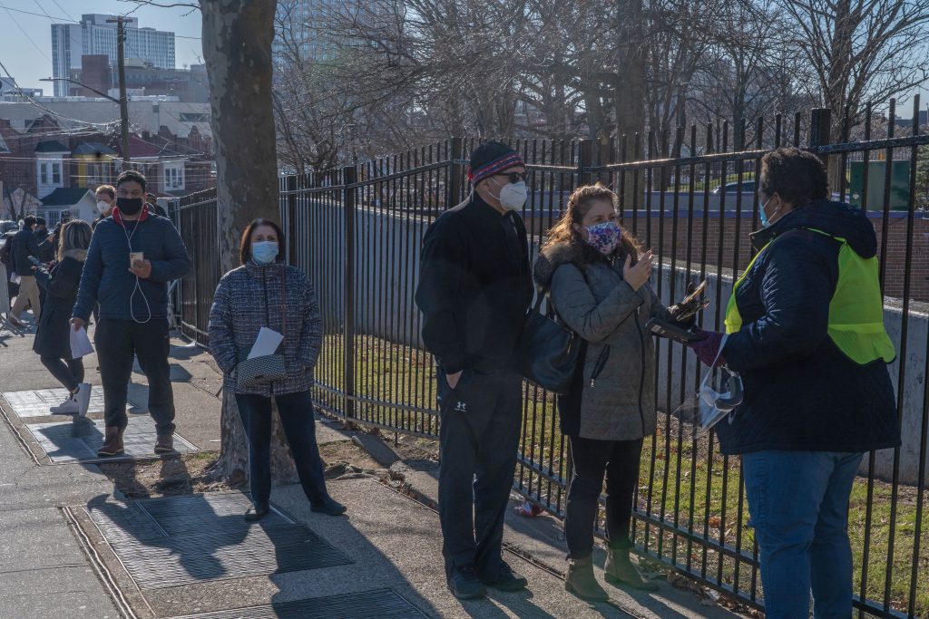 People who are eligible and registered wait in line to get COVID-19 vaccine at NYC Health Department Vaccine Hub at Hillcrest High School in Queens.